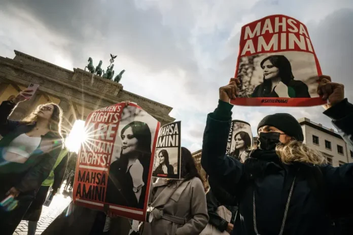 Protesters holding banners with a picture of Masha Amini during a rally in reaction to her death