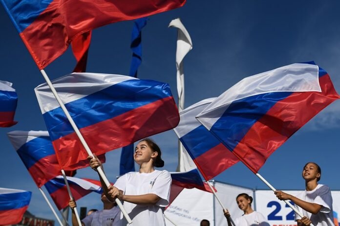 Молодежь с российскими флагами идет по площади Маркса в Новосибирске, 22 августа 2019 года
